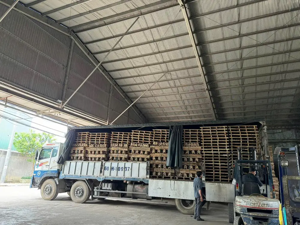 xe nâng bốc pallet gỗ tràm lên xe tải trong xưởng