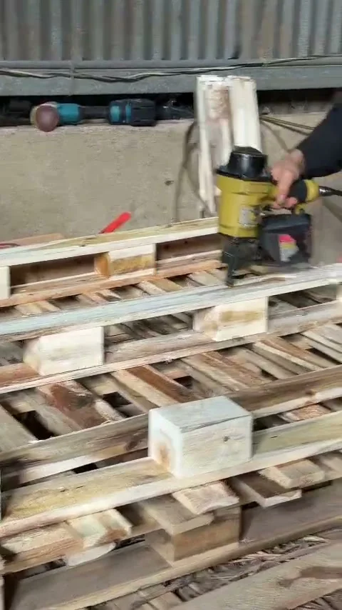 thợ dùng súng bắn đinh đóng nan pallet gỗ chân khối tại xưởng