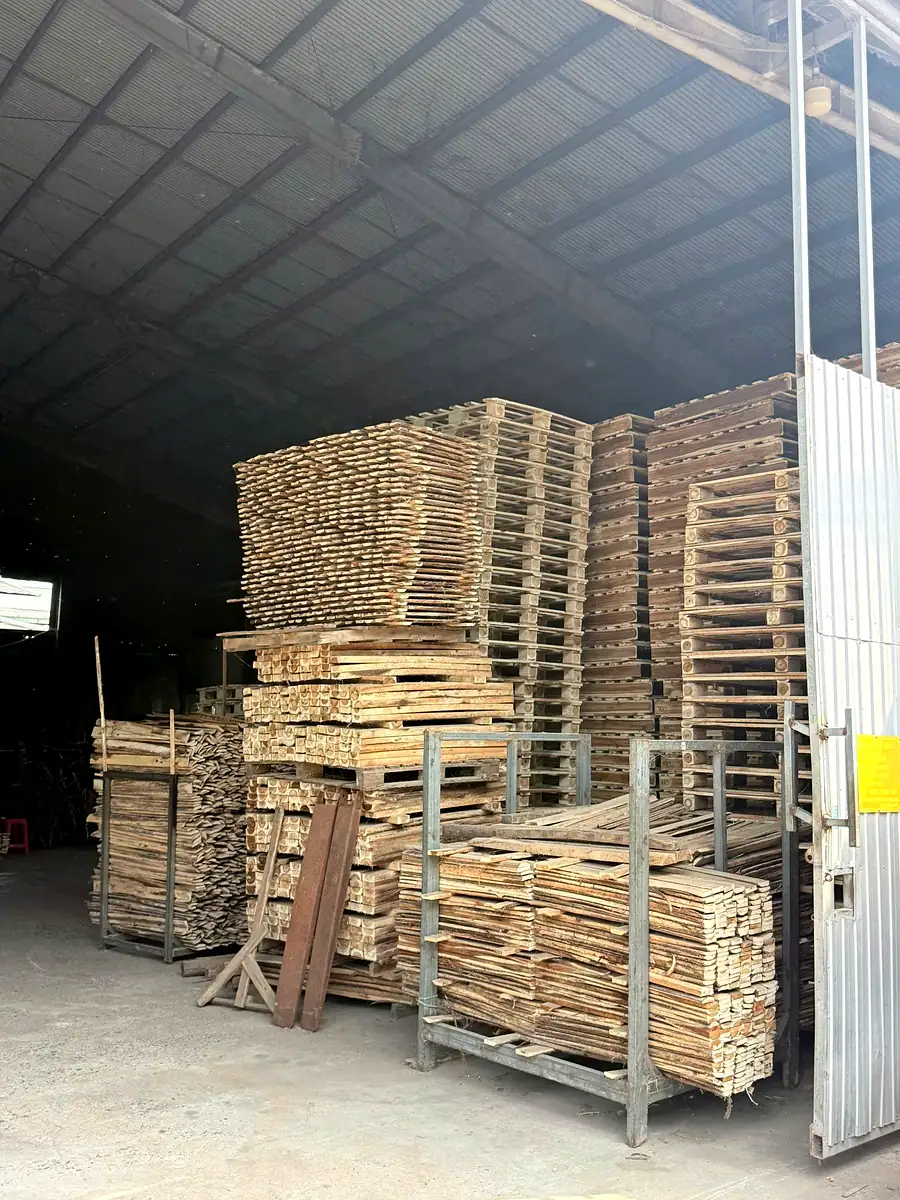 pallet gỗ tràm thành phẩm xếp chồng cao cạnh cửa kho xưởng chờ giao