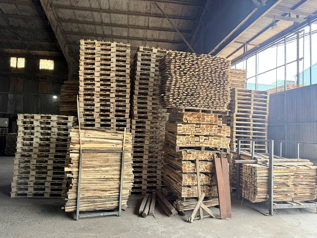 chồng pallet gỗ tràm mới và phôi gỗ xẻ gần cửa xưởng
